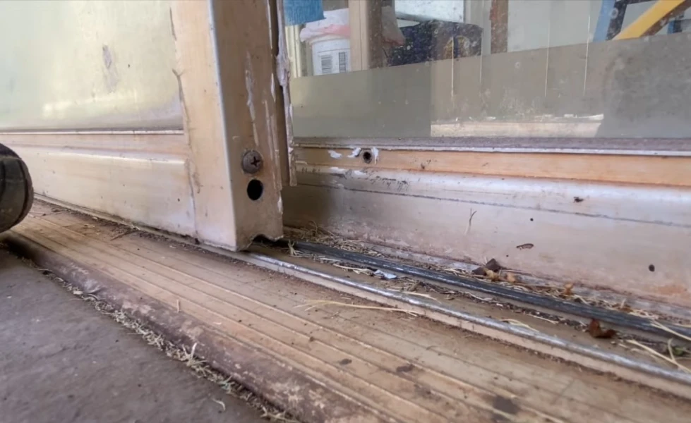 Sliding glass door off its track being repaired and realigned by a Fort Myers technician